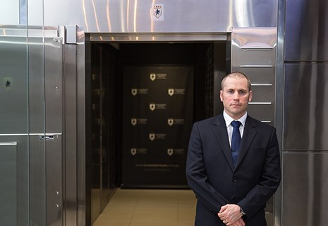 Custodian Vaults security guard standing in front of safety deposit boxes and vault door